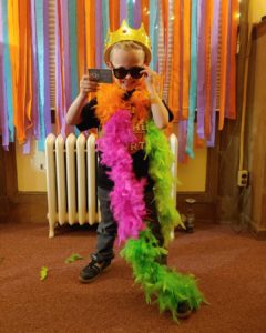 Young man with library card in sunglasses and feather boa smiling